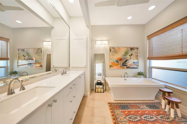 bathroom with a washtub, vanity, and tile patterned flooring