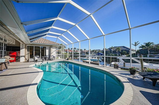 view of swimming pool featuring glass enclosure, a water view, a patio, and a boat dock