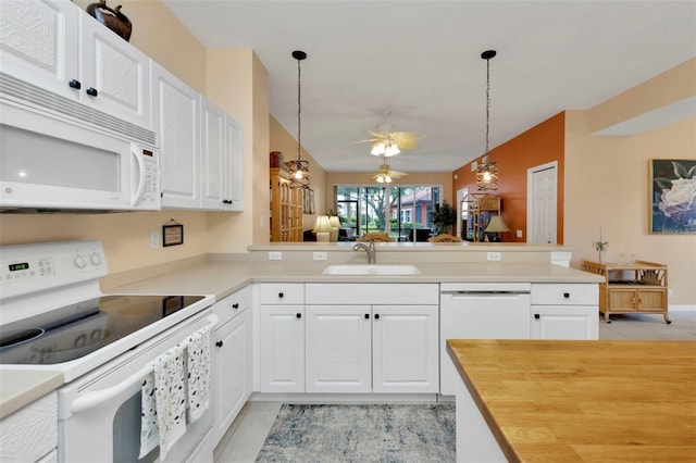 kitchen with pendant lighting, kitchen peninsula, white appliances, and sink