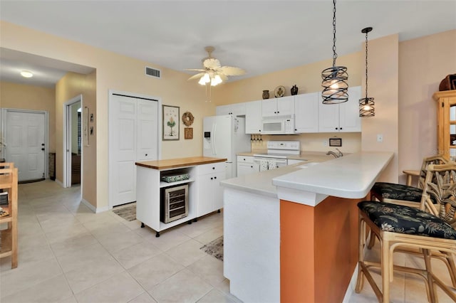 kitchen featuring white cabinetry, beverage cooler, hanging light fixtures, kitchen peninsula, and white appliances