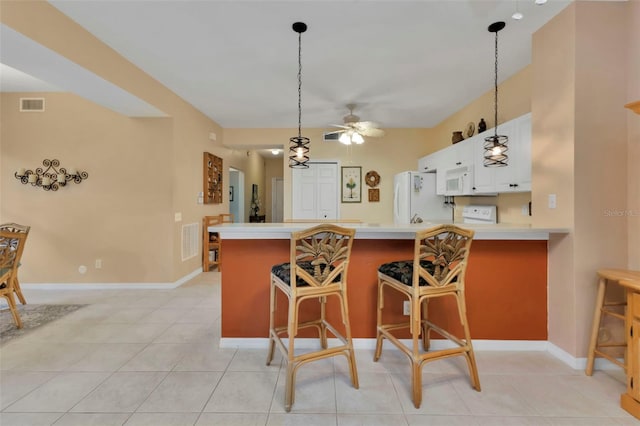 kitchen featuring a kitchen bar, kitchen peninsula, white appliances, white cabinets, and light tile patterned flooring