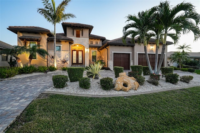 view of front of home with a front lawn, a garage, and french doors