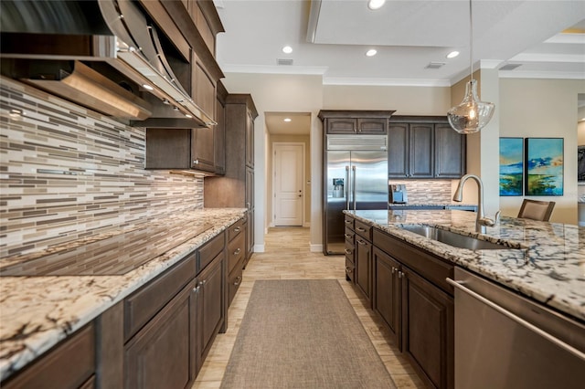 kitchen with decorative light fixtures, backsplash, sink, crown molding, and stainless steel appliances