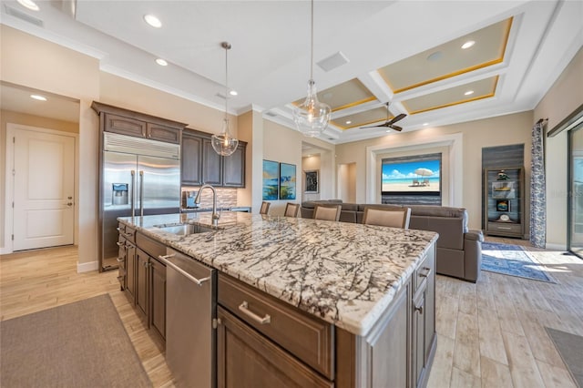 kitchen with stainless steel appliances, sink, a kitchen island with sink, light hardwood / wood-style flooring, and coffered ceiling