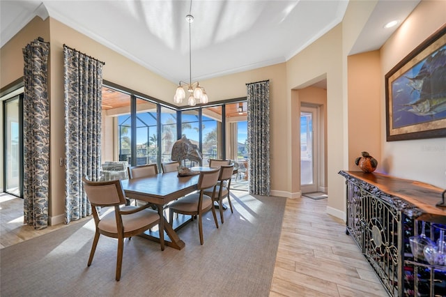 dining area featuring light hardwood / wood-style floors, crown molding, and a notable chandelier