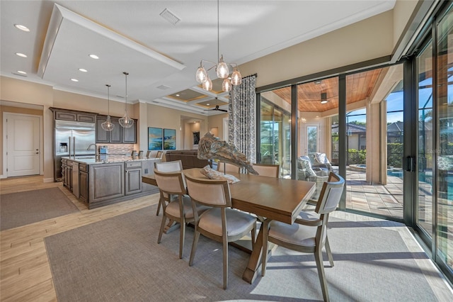 dining space with an inviting chandelier, ornamental molding, and sink