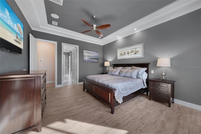 bedroom with ceiling fan, ornamental molding, a raised ceiling, and light hardwood / wood-style flooring