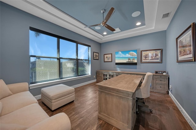 office space featuring ceiling fan, dark hardwood / wood-style floors, and a tray ceiling