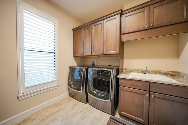 laundry area with light hardwood / wood-style floors, sink, washing machine and clothes dryer, and cabinets