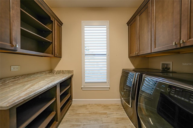 laundry area featuring cabinets, separate washer and dryer, and light hardwood / wood-style flooring