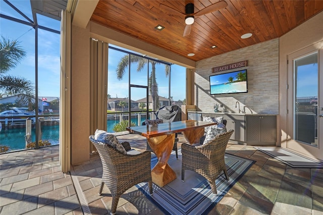 sunroom featuring a water view, ceiling fan, and wooden ceiling