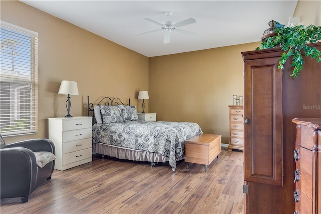 bedroom with multiple windows, ceiling fan, and hardwood / wood-style flooring