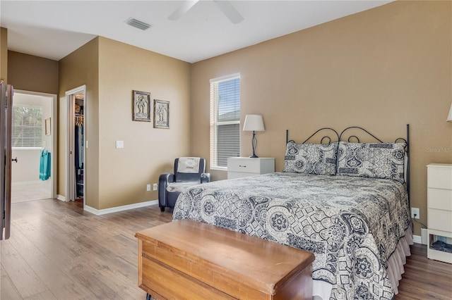 bedroom featuring wood-type flooring, a spacious closet, a closet, and ceiling fan