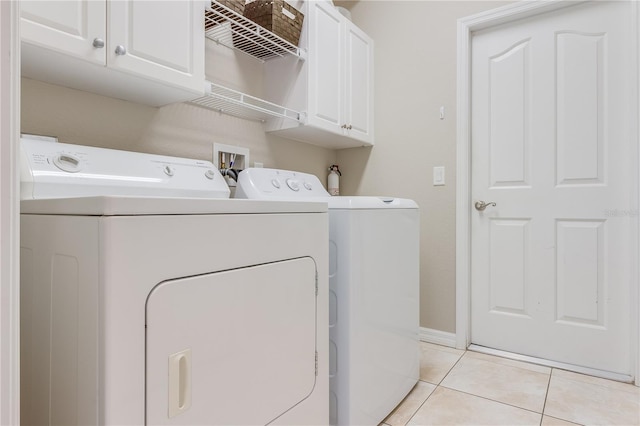 washroom with cabinets, light tile patterned floors, and washing machine and clothes dryer