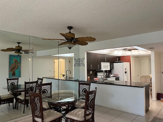 dining space featuring light tile patterned floors, sink, and a textured ceiling