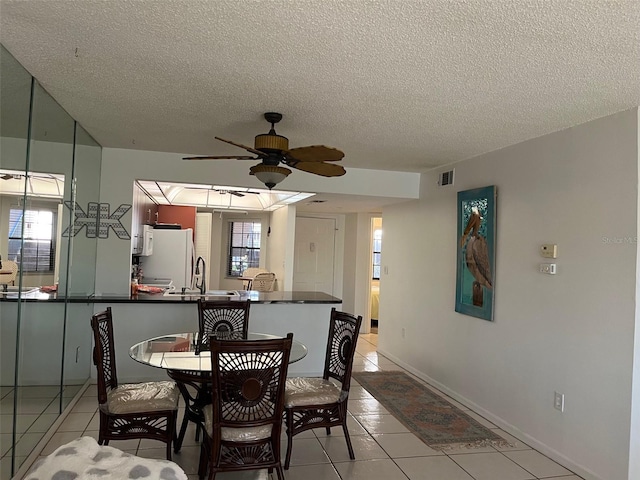 dining space with a textured ceiling, ceiling fan, and light tile patterned flooring