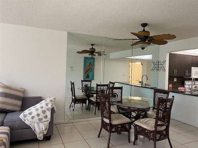 dining area featuring light tile patterned flooring, sink, a textured ceiling, and ceiling fan