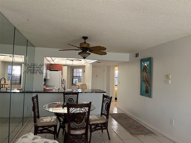 tiled dining space featuring sink, a textured ceiling, plenty of natural light, and ceiling fan