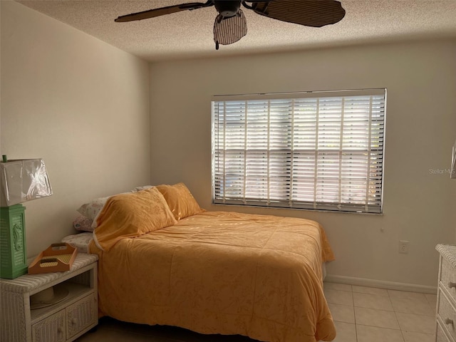 bedroom with a textured ceiling, ceiling fan, and light tile patterned flooring