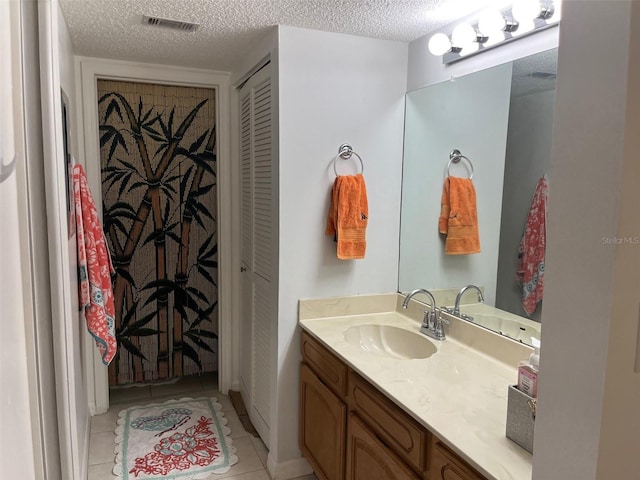 bathroom featuring vanity, tile patterned floors, and a textured ceiling