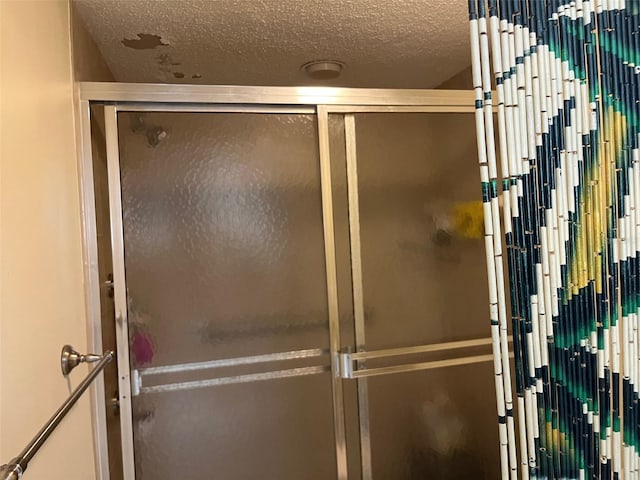 bathroom featuring a shower with door and a textured ceiling