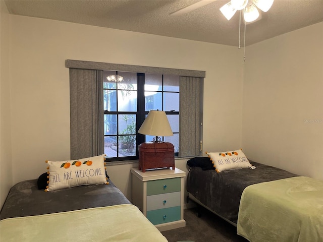 bedroom with ceiling fan, dark carpet, and a textured ceiling