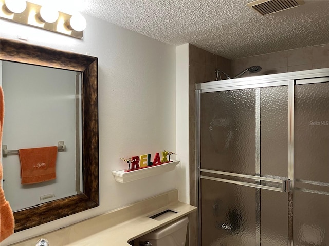 bathroom with walk in shower, toilet, and a textured ceiling