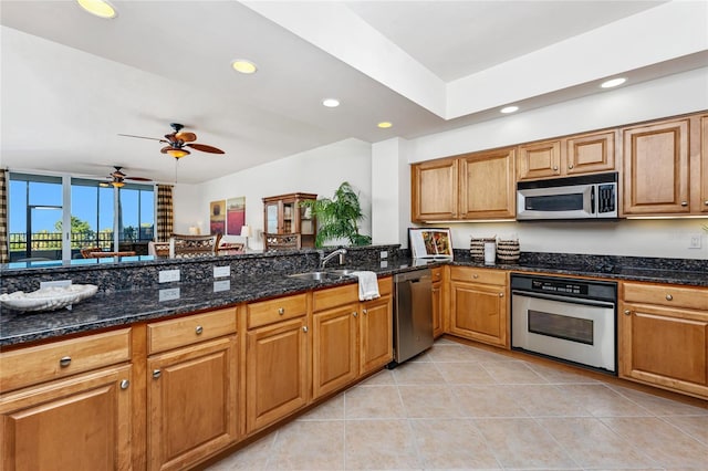 kitchen with sink, dark stone countertops, light tile patterned floors, kitchen peninsula, and appliances with stainless steel finishes