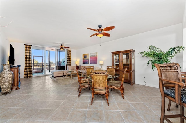 tiled dining area featuring ceiling fan and a wall of windows