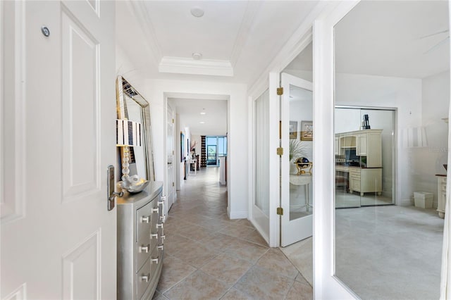 corridor with crown molding, a raised ceiling, and light tile patterned floors