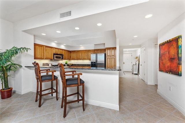 kitchen featuring a kitchen bar, light tile patterned floors, kitchen peninsula, and appliances with stainless steel finishes