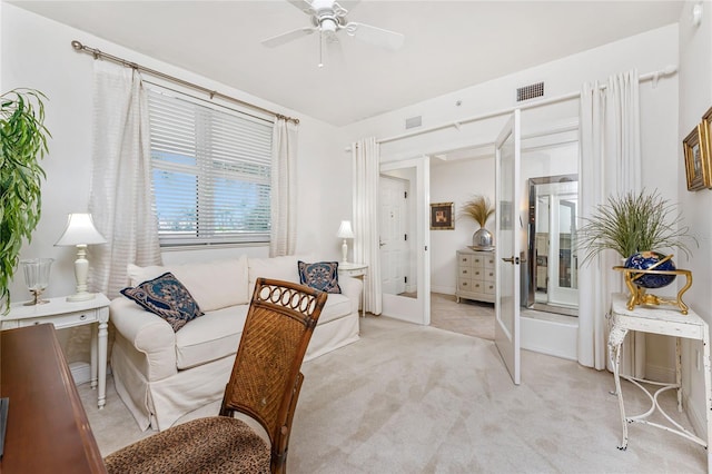 living area with ceiling fan, light colored carpet, and french doors