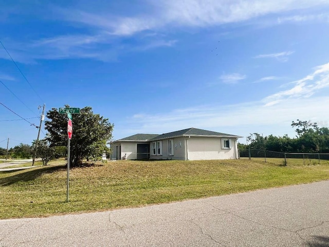 ranch-style home with a front lawn, fence, and stucco siding