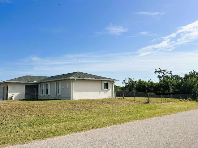 exterior space featuring stucco siding, fence, and a yard