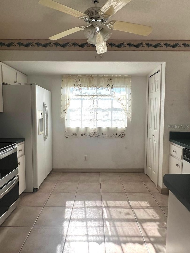 kitchen with dark countertops, white cabinets, range with two ovens, and light tile patterned flooring