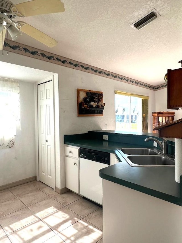 kitchen featuring dark countertops, visible vents, dishwasher, and a sink