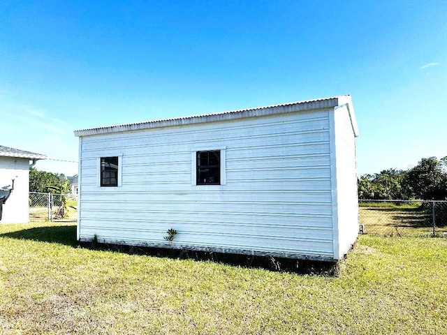 view of side of property featuring an outbuilding, a yard, and fence