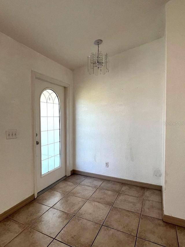 unfurnished dining area with a chandelier, light tile patterned floors, baseboards, and a healthy amount of sunlight