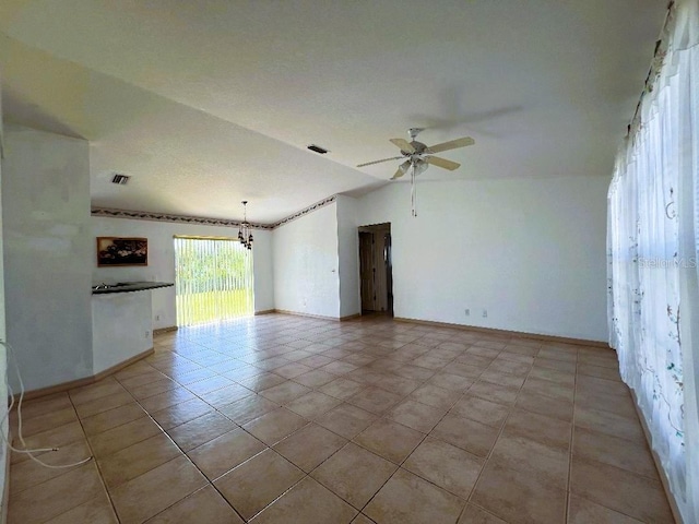 empty room with ceiling fan with notable chandelier, light tile patterned floors, lofted ceiling, and visible vents