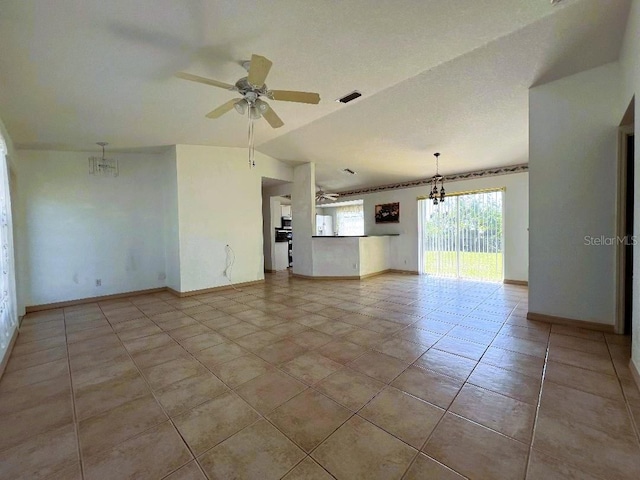 empty room with visible vents, light tile patterned flooring, vaulted ceiling, baseboards, and ceiling fan with notable chandelier