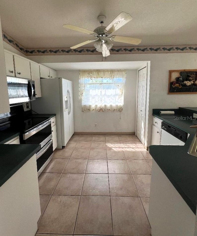 kitchen featuring light tile patterned floors, a ceiling fan, dark countertops, stainless steel appliances, and white cabinetry