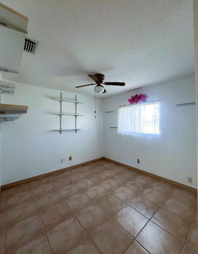 unfurnished room with visible vents, ceiling fan, a textured ceiling, and baseboards