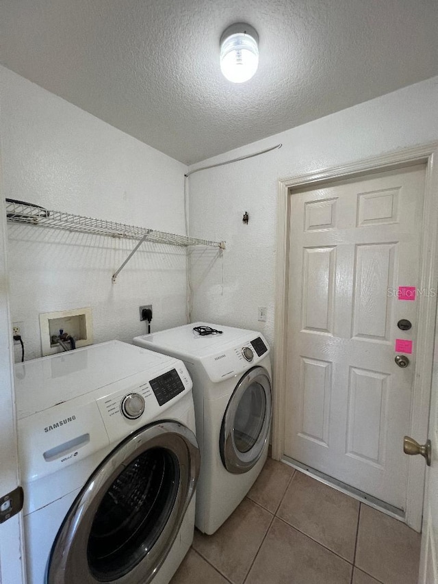 clothes washing area featuring a textured ceiling, laundry area, washing machine and clothes dryer, and tile patterned floors