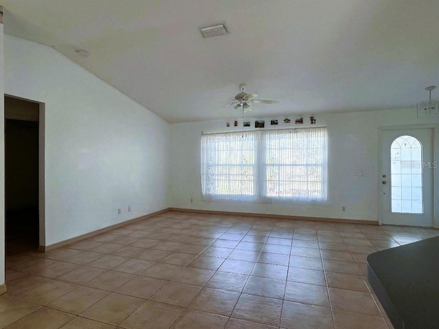 spare room with baseboards, visible vents, a ceiling fan, vaulted ceiling, and light tile patterned flooring