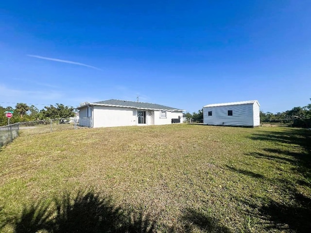 rear view of property featuring fence and a yard