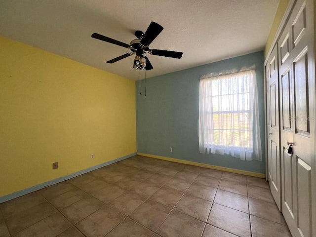 spare room with ceiling fan, baseboards, and tile patterned floors