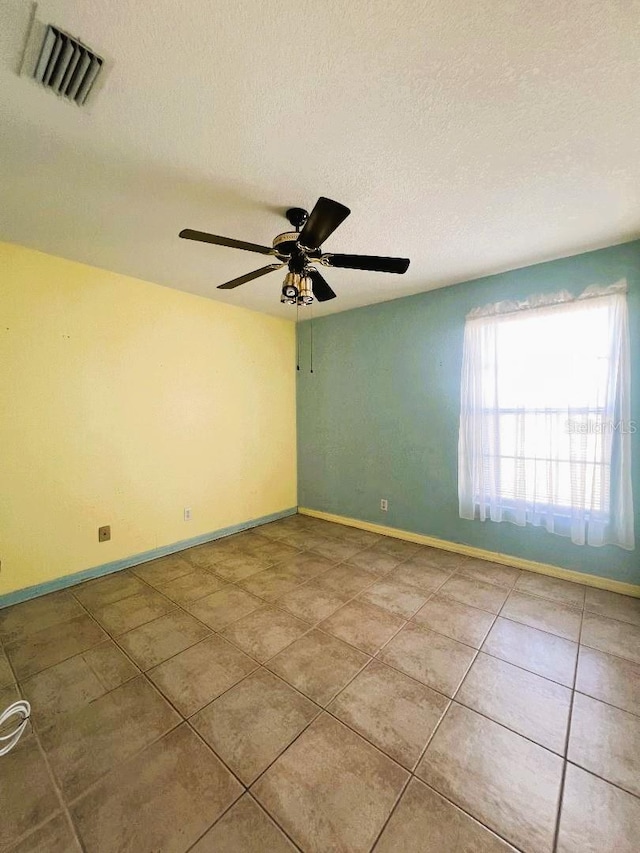 spare room featuring baseboards, visible vents, ceiling fan, a textured ceiling, and light tile patterned flooring