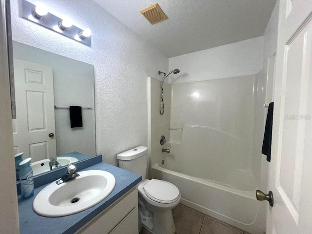 bathroom featuring visible vents, a textured wall, toilet, vanity, and tile patterned floors