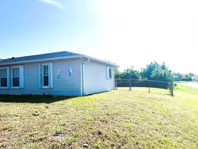 view of home's exterior with stucco siding, a lawn, and fence