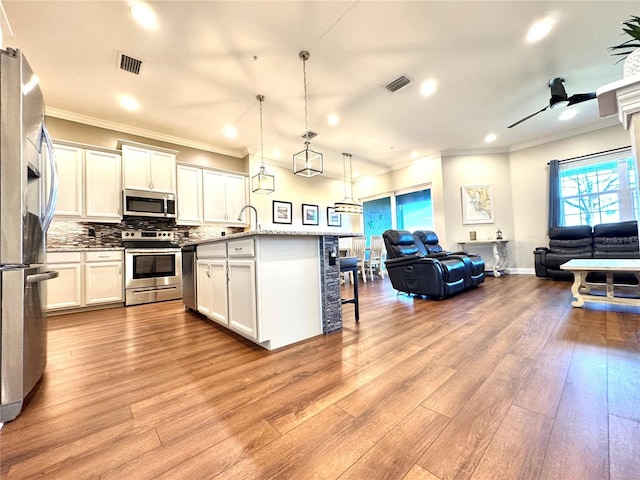 kitchen with white cabinetry, ceiling fan, hanging light fixtures, stainless steel appliances, and a breakfast bar